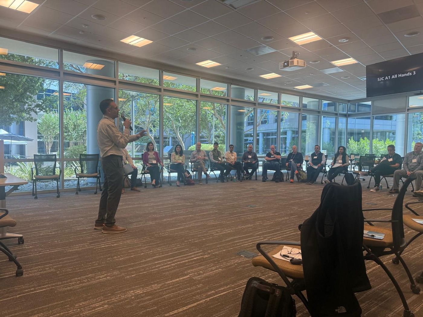 A TLEX facilitator guiding a team standing in a circle in a corporate meeting room